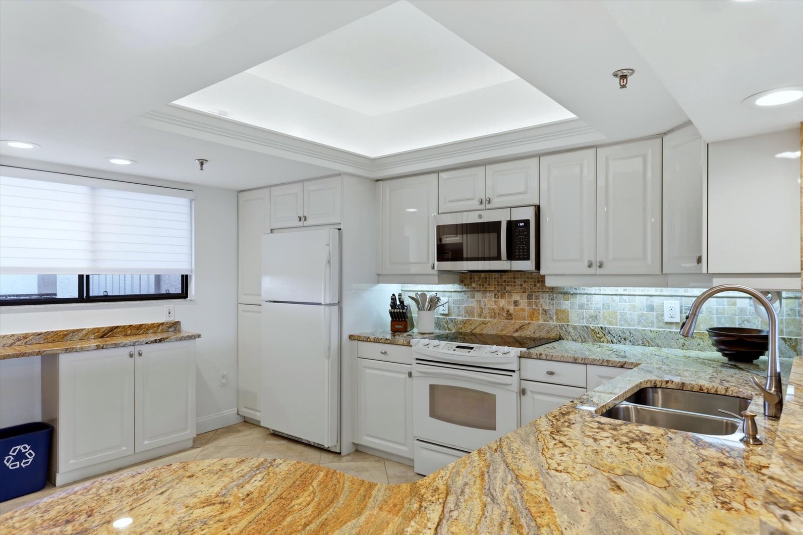 You'll love cooking in this bright, fully-equipped kitchen with stunning granite countertops, white cabinetry, and a beautiful skylight overhead.