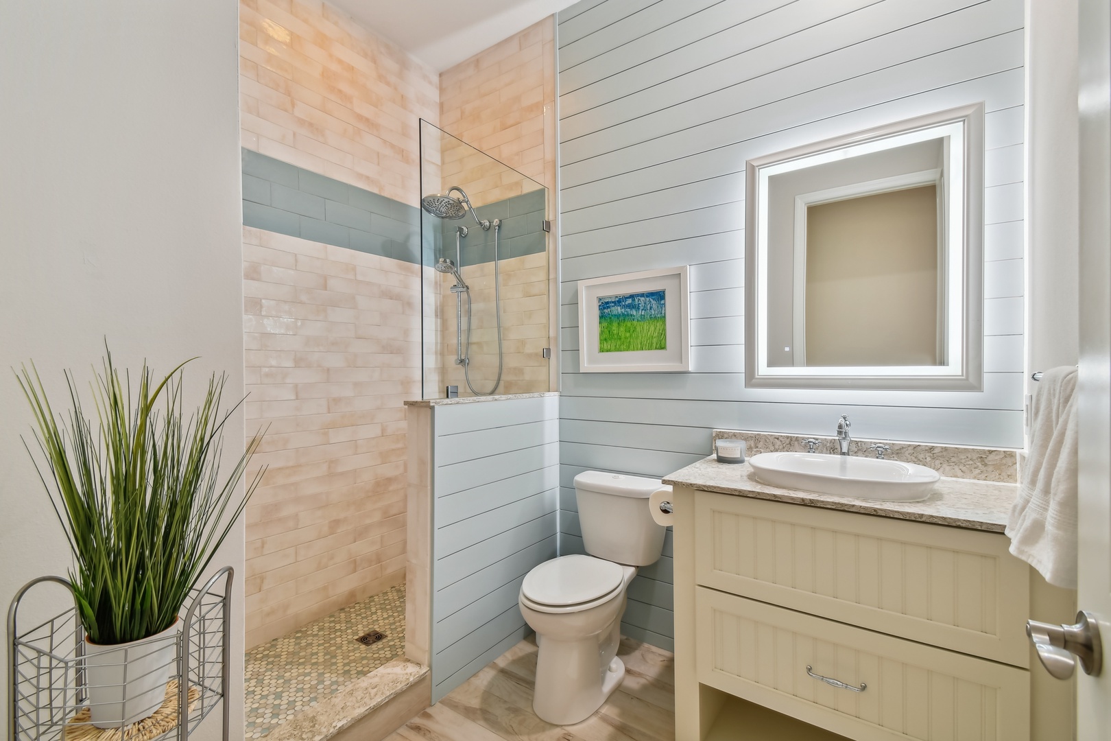 Refresh in your stylish bathroom featuring a glass-enclosed shower with coastal-inspired tile work and modern vanity with granite countertops.