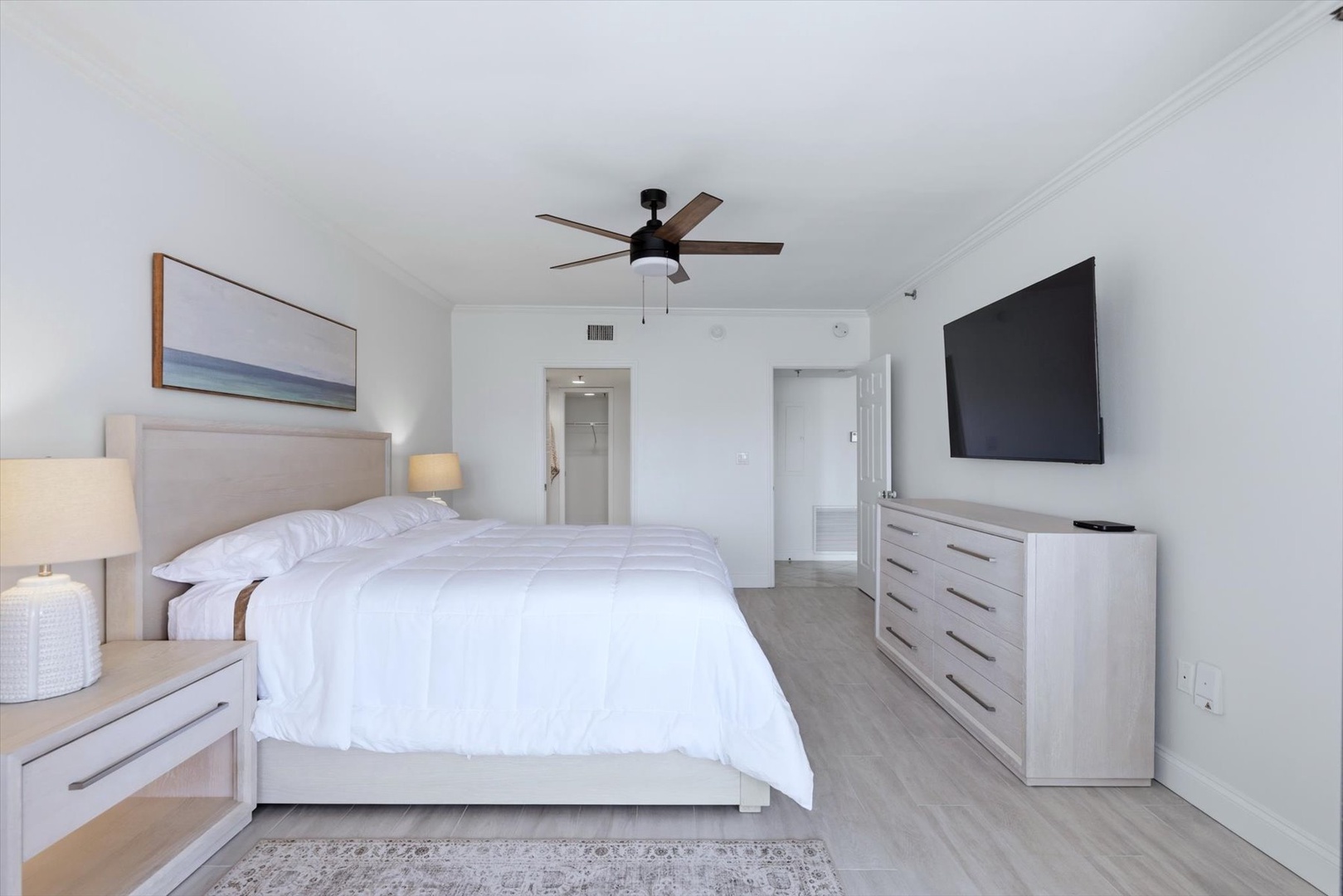 Sink into crisp white linens in your serene bedroom, complete with modern furnishings and flat-screen TV for perfect relaxation.