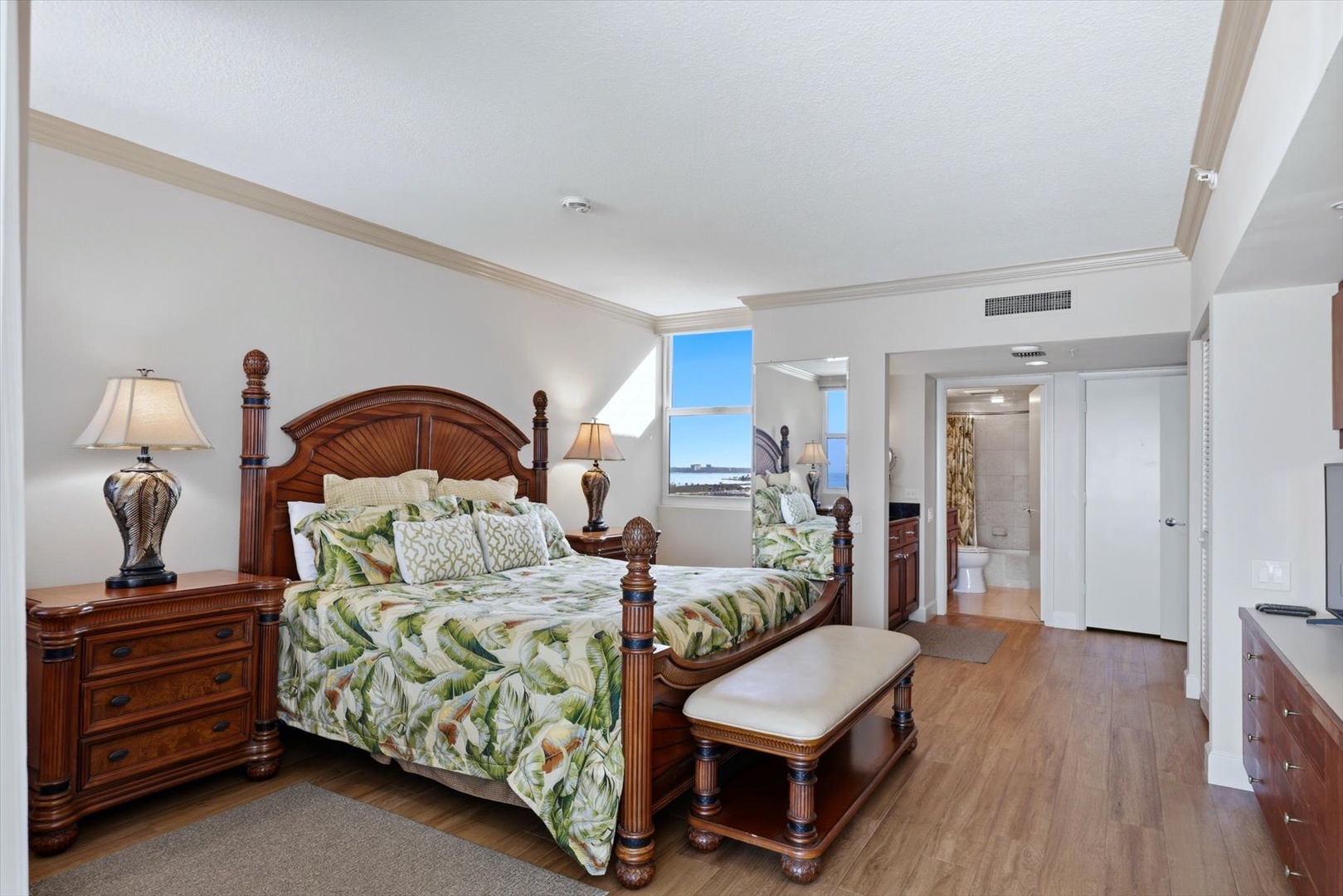 Sink into this elegant four-poster bed with tropical linens while enjoying stunning water views through your private window.