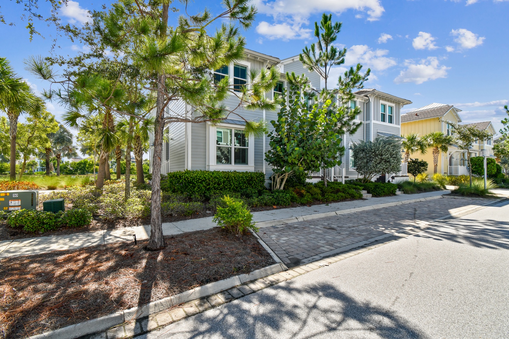 Charming coastal-style vacation home featuring tropical landscaping and peaceful residential setting with convenient paved driveway access.
