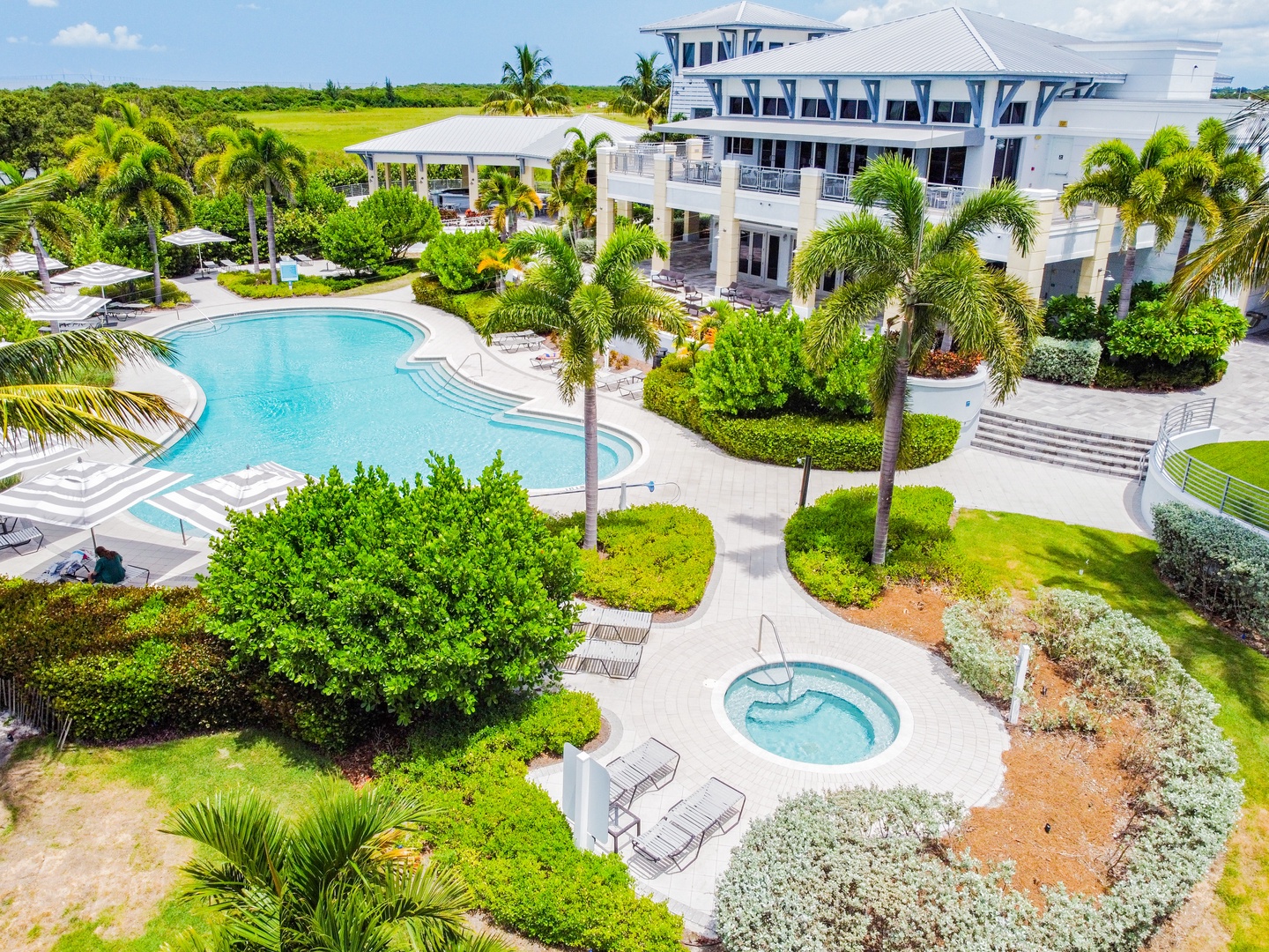 Stunning aerial view of this luxurious tropical estate featuring pristine pool, spa, and lush landscaping surrounded by swaying palms.