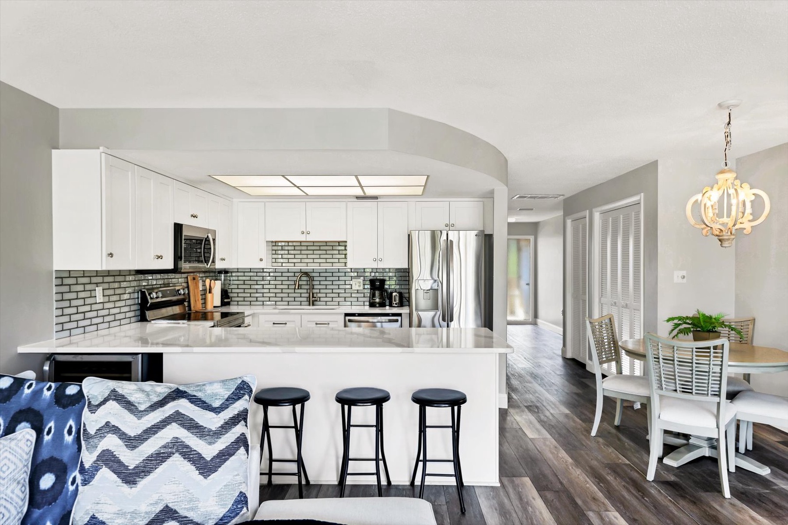 Your modern kitchen invites culinary adventures with sleek white cabinets, granite counters, and a breakfast bar perfect for morning coffee.