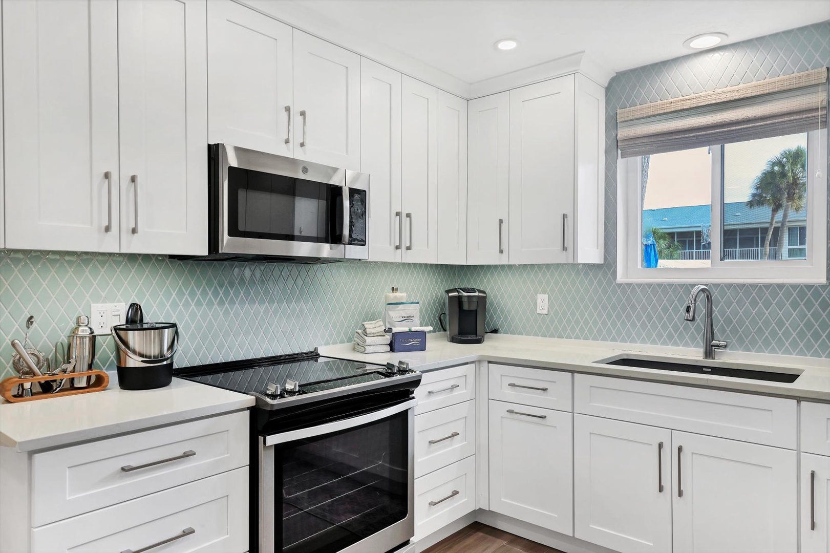 Your bright, modern kitchen features crisp white cabinets and elegant aqua tile backsplash, perfect for preparing meals with coastal views.