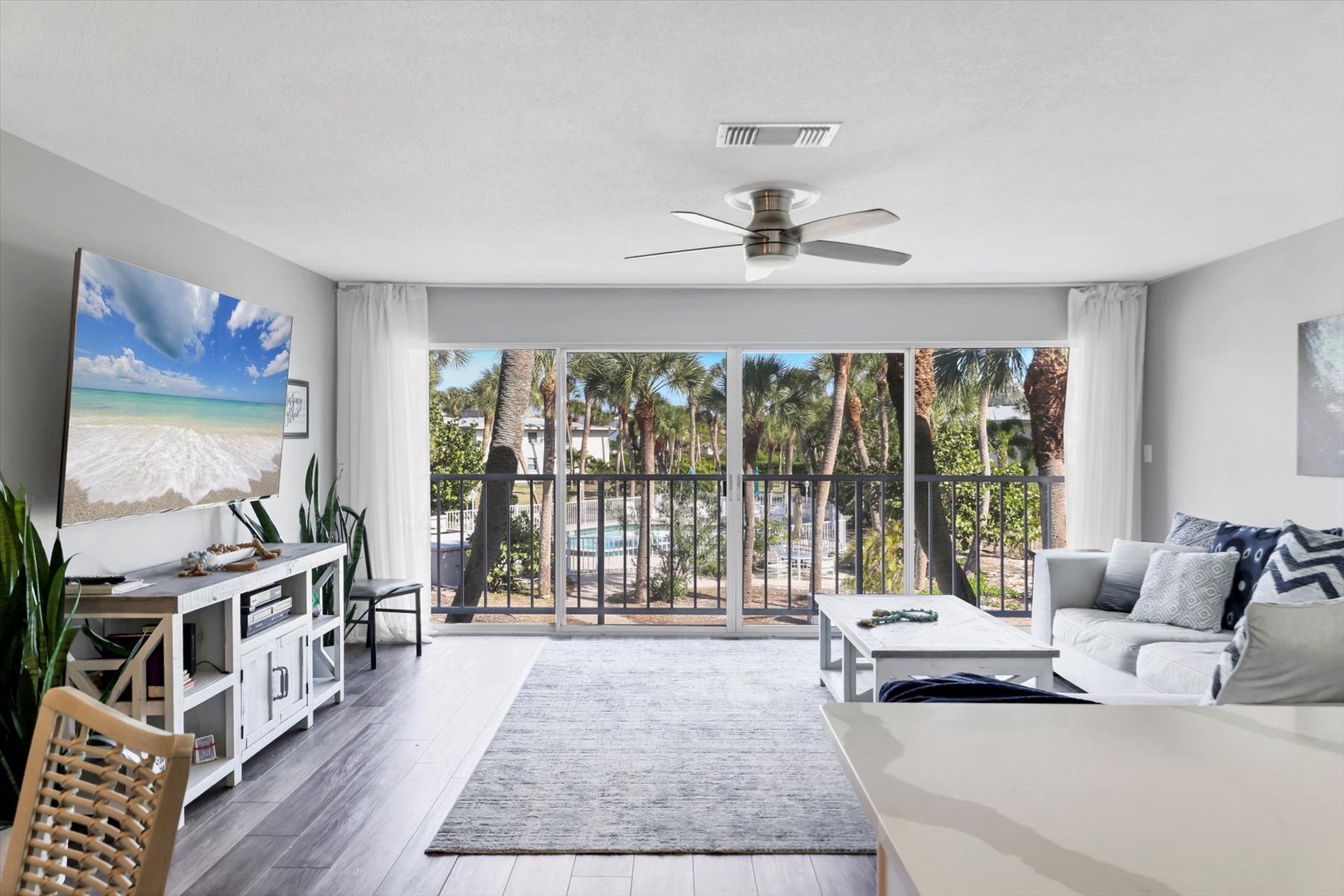 Your bright living room opens to a private balcony with tropical pool views, perfect for relaxing with coastal decor and modern comforts.