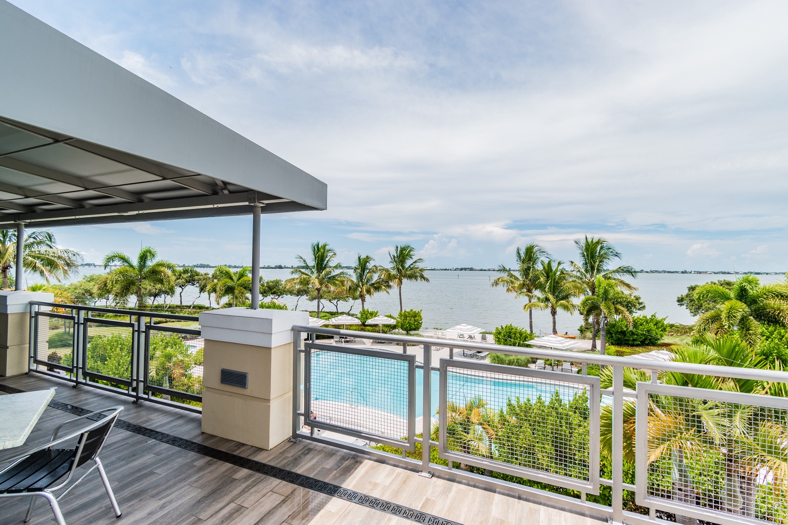 Your private balcony overlooks tropical paradise with pool and ocean views stretching to the horizon.
