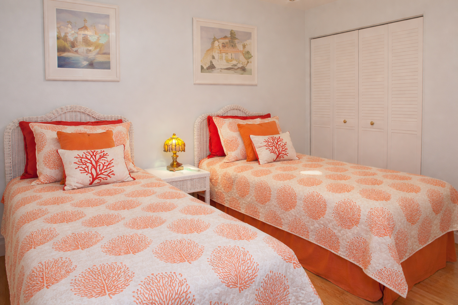 Unwind in your serene twin bedroom with coral-themed linens and charming nautical artwork creating a peaceful coastal retreat.