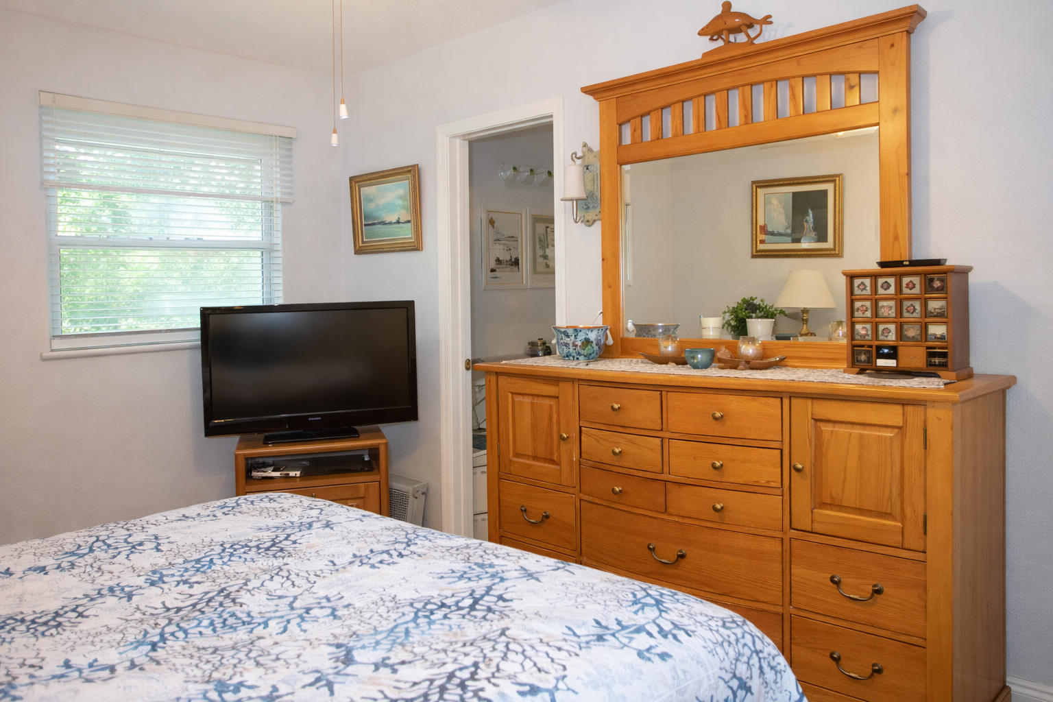 Relax in your cozy bedroom with handcrafted wood furniture, flat-screen TV, and peaceful garden views through bright windows.