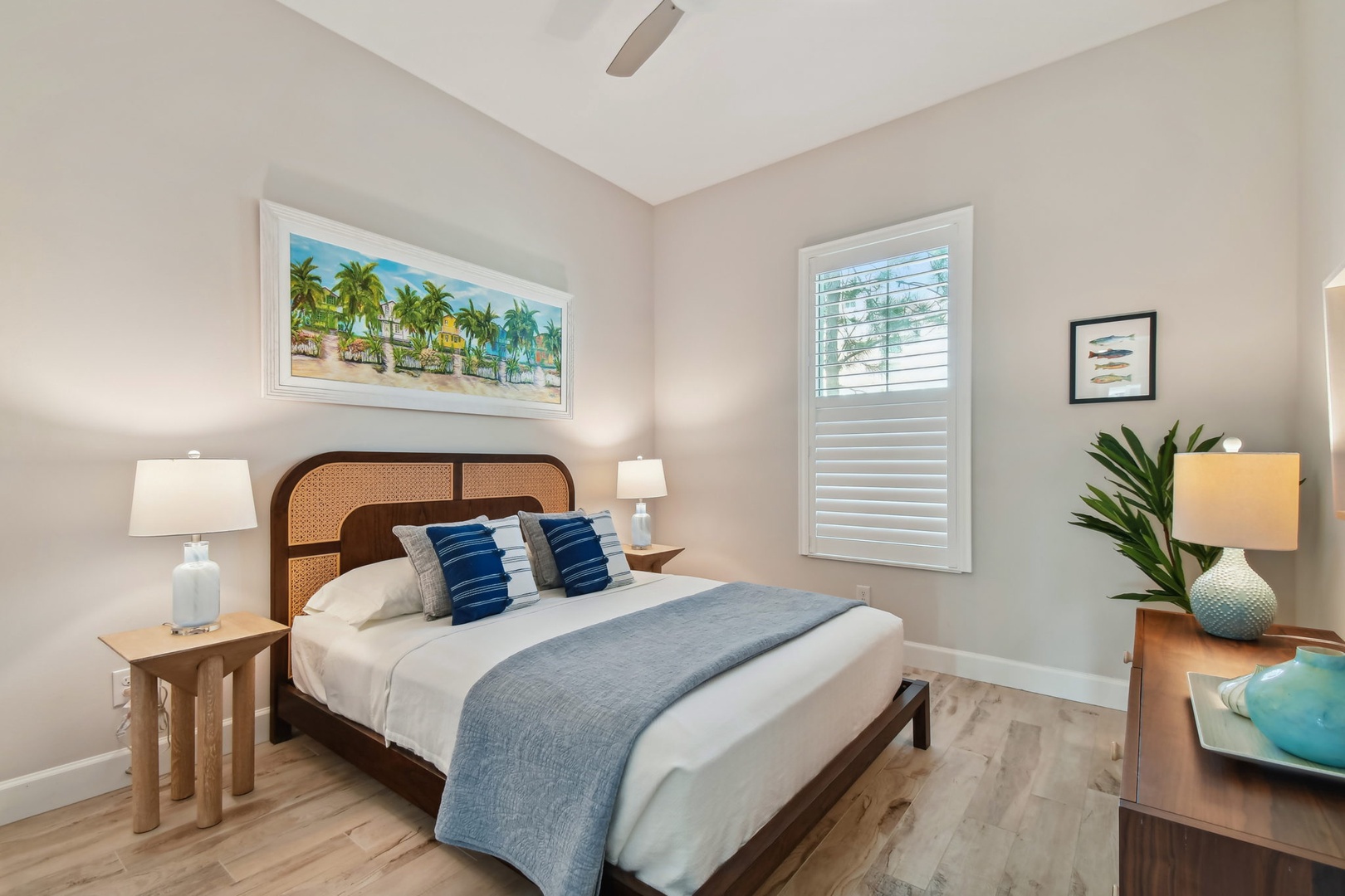 Sink into this coastal-inspired bedroom where tropical artwork and ocean-blue accents create your perfect retreat for peaceful nights.