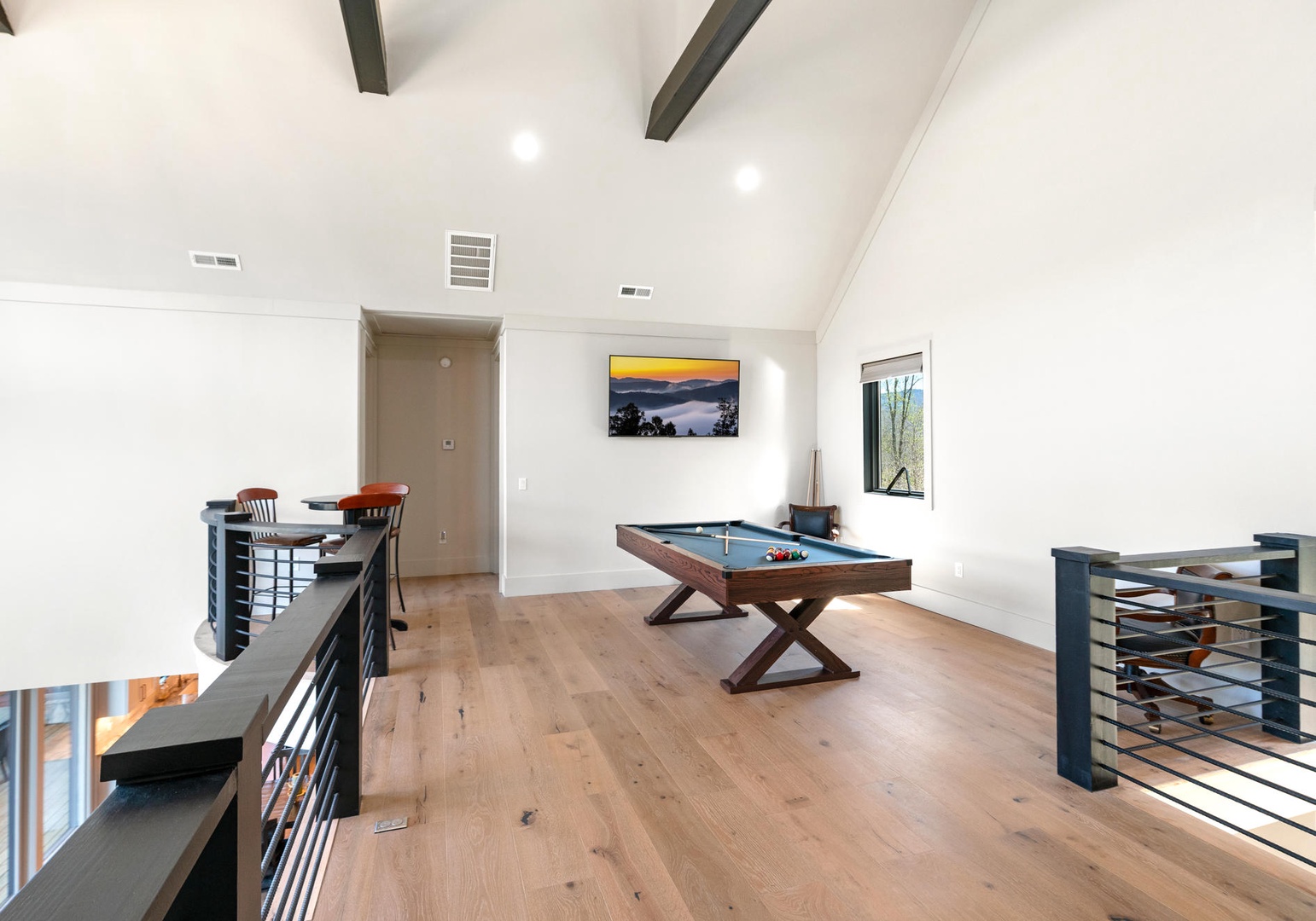 Your upstairs game room offers endless entertainment with a sleek pool table and seating area, all bathed in natural light.