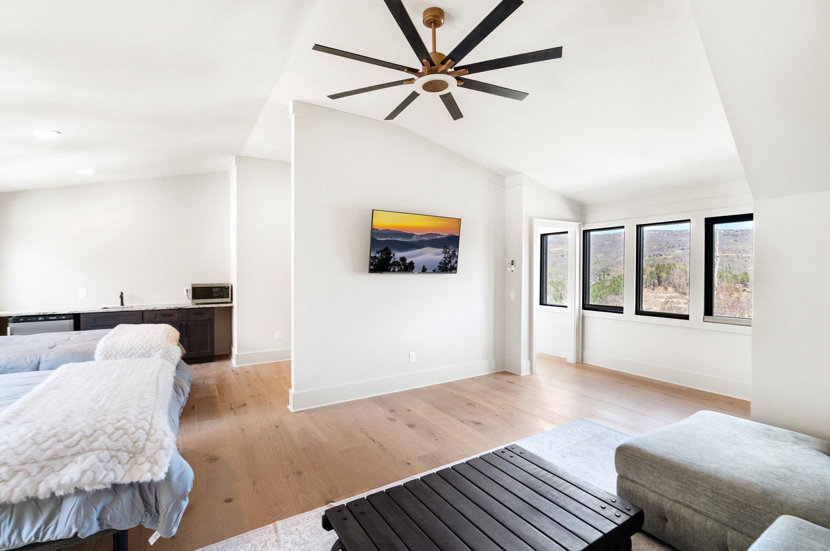 Drift off in your serene master suite featuring soaring ceilings, warm wood floors, and panoramic windows framing stunning desert vistas.