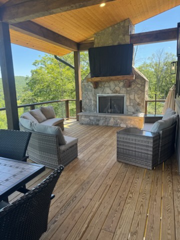 Picture yourself unwinding on this covered deck, surrounded by rolling green hills and fresh country air. Cozy seating and a stone fireplace create the perfect spot to sip morning coffee or relax under the stars.