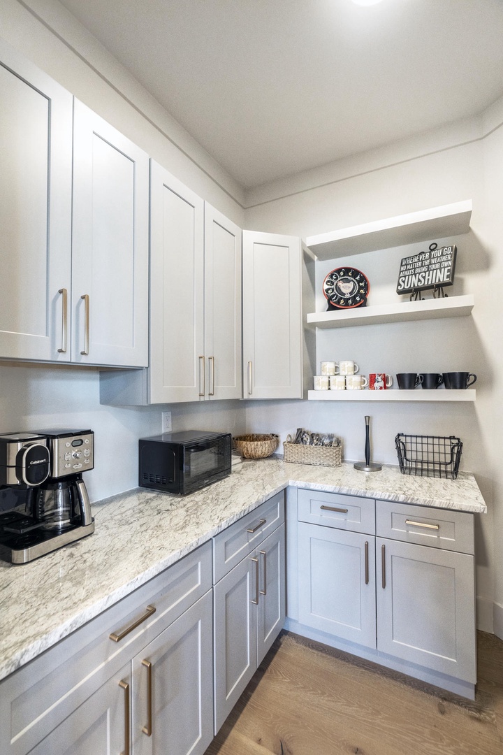 Your own coffee station awaits with granite counters, premium appliances, and open shelving for morning rituals.