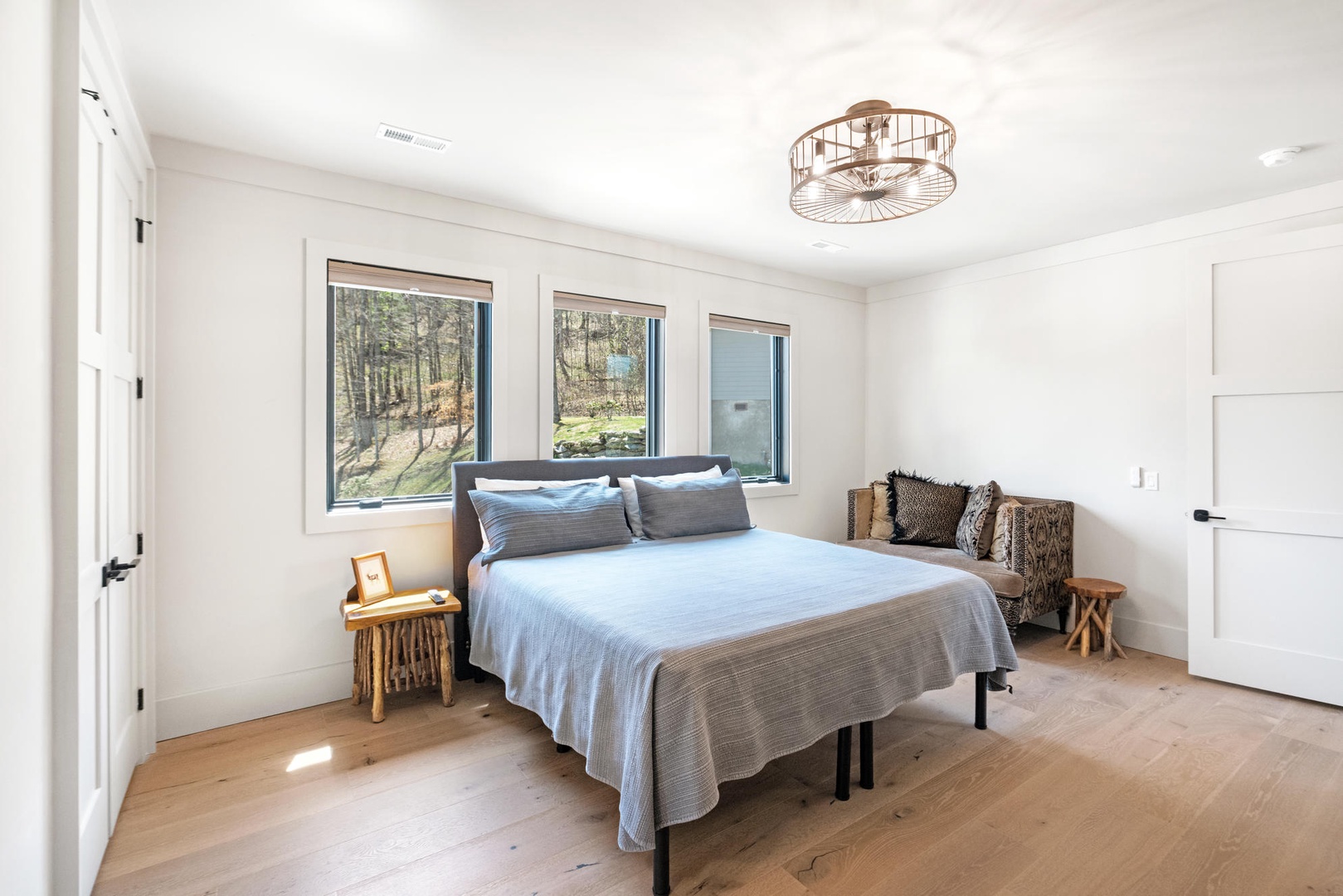 Wake up in this serene bedroom where natural light streams through large windows, revealing peaceful forest views that greet you each morning.