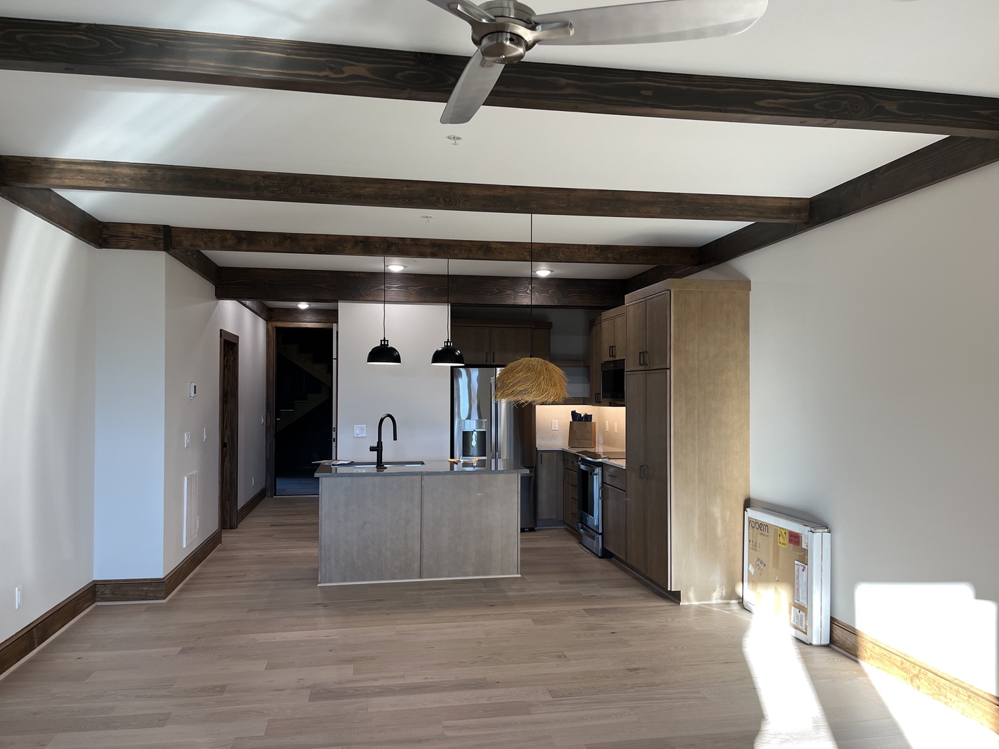Open-concept retreat with striking wood beam ceilings, fully-equipped modern kitchen, and large island with stainless appliances and ample counter space for culinary adventures.