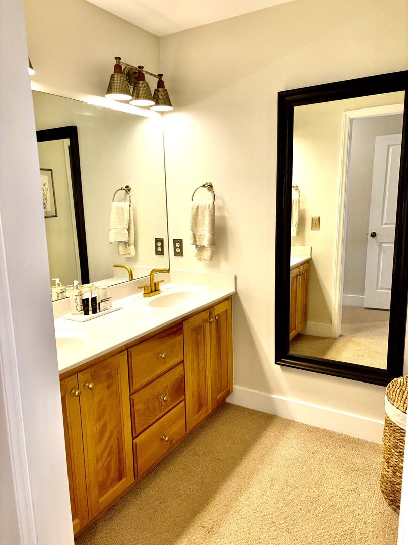 Private en-suite bath with dual vanities and warm, updated finishes.