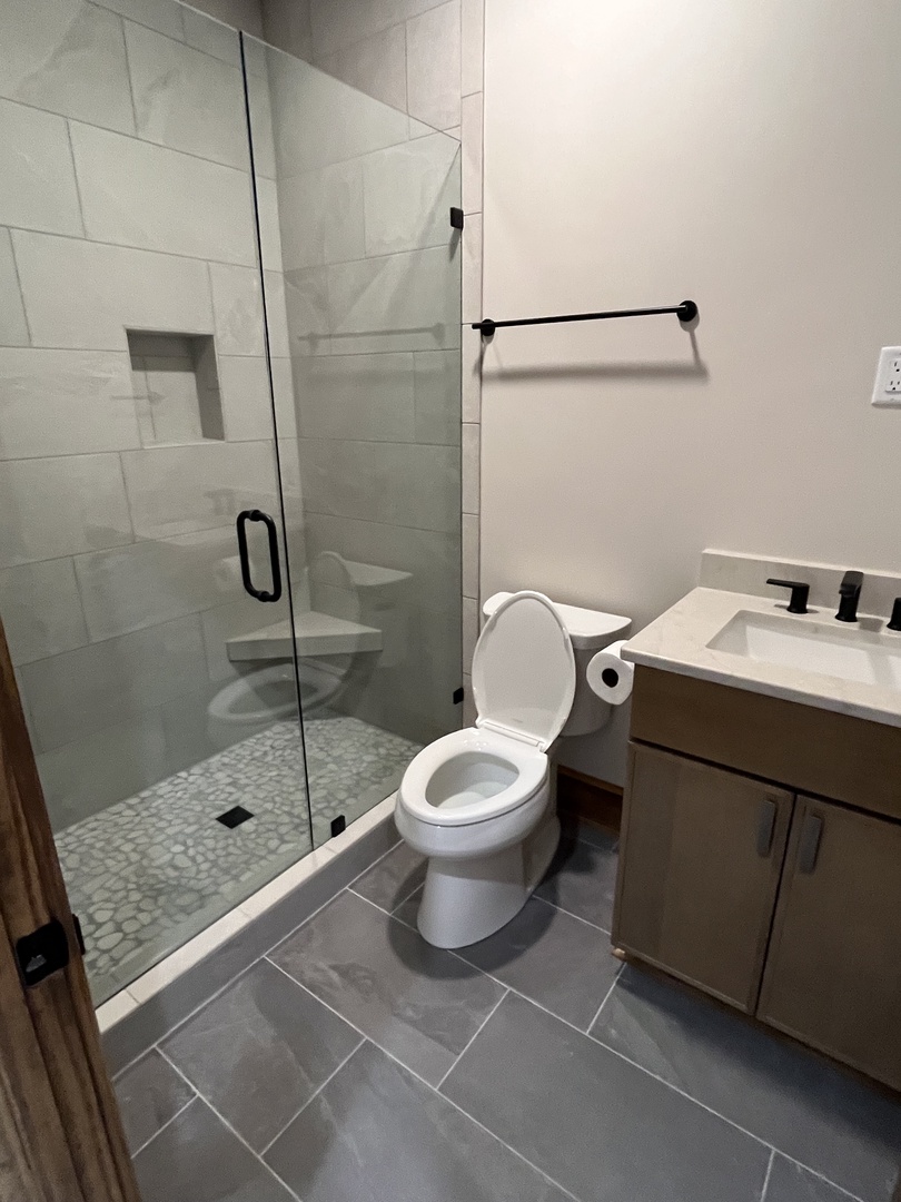 Your private bathroom features modern fixtures, a sleek glass shower enclosure, and elegant tile work throughout.