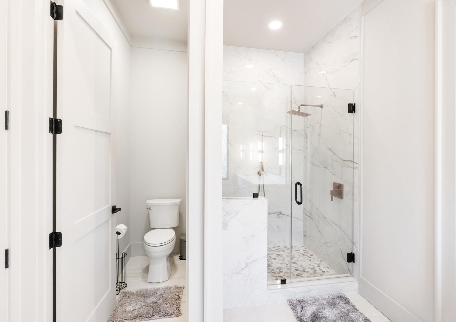 Step into your pristine marble sanctuary where elegant glass-enclosed shower and private toilet await your morning rituals.