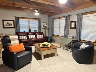 Step into your cozy retreat with rustic wood beams overhead and plenty of natural light streaming through. Sink into the plush sofa, prop up your feet on the coffee table, and let the day melt away in this inviting living space.