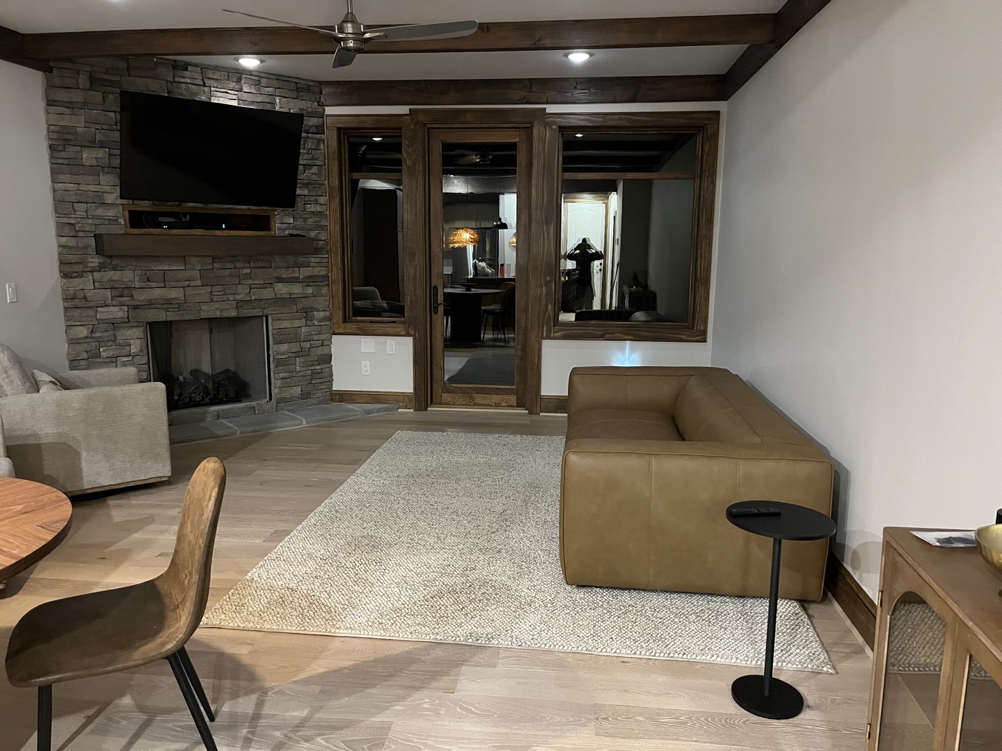 Unwind in your spacious living area featuring a cozy stone fireplace, modern entertainment setup, and sleek leather sofa—perfect for relaxing evenings after exploring nearby attractions.