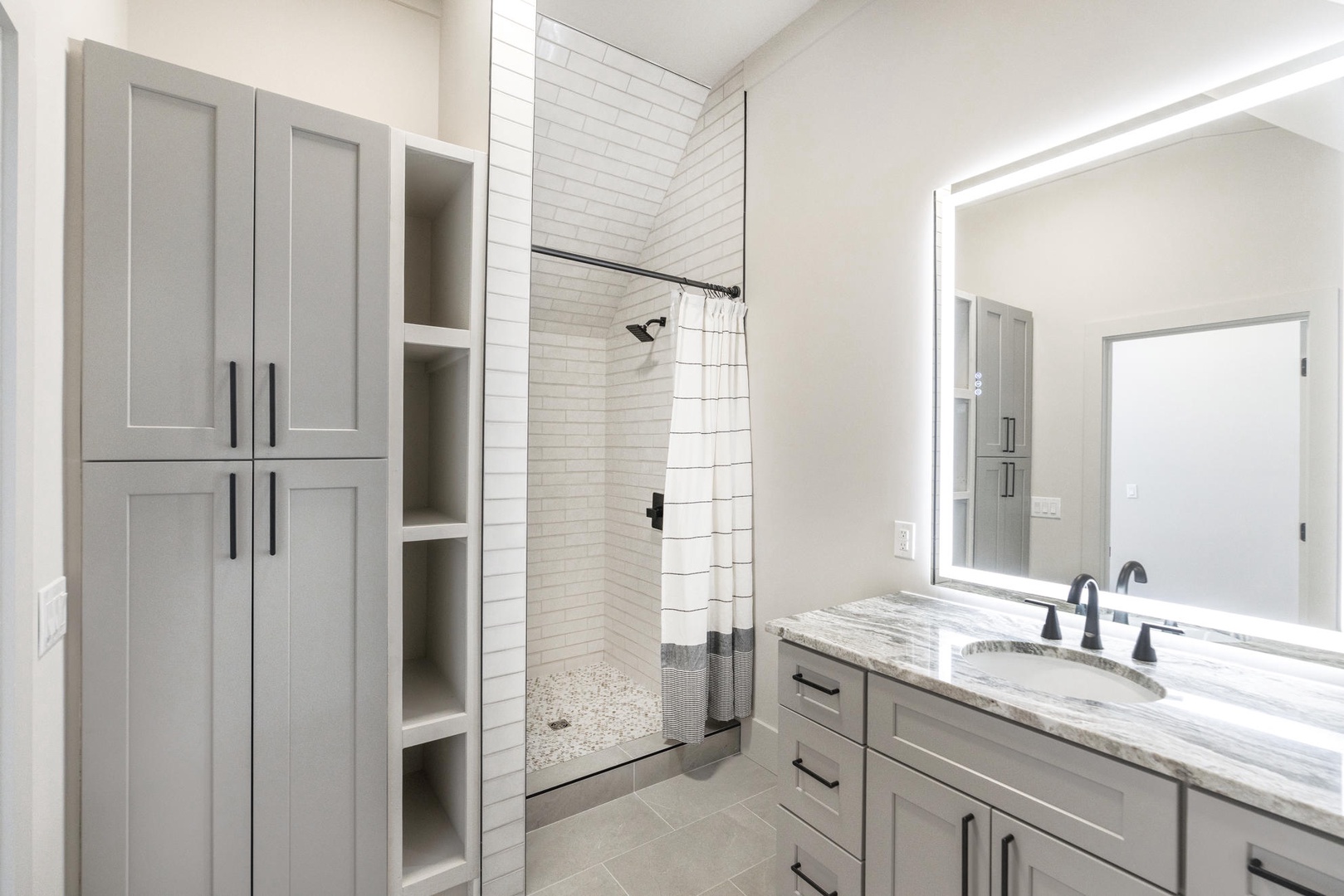 Step into your elegant bathroom featuring granite countertops, custom cabinetry, and a luxurious subway-tiled shower.