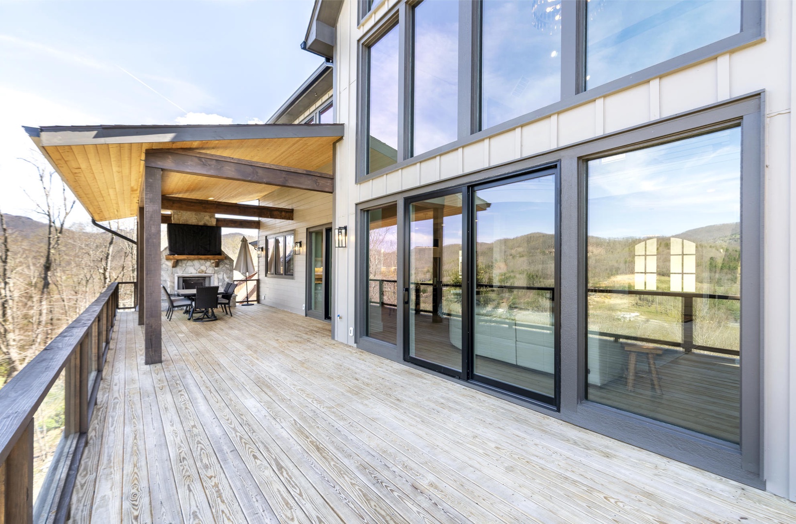 Modern mountain retreat with expansive deck overlooking forested hills and distant peaks.