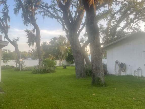 The property sits nestled in a peaceful setting, surrounded by mature live oak trees draped with Spanish moss and a sprawling lawn that captures the serene beauty of the area.