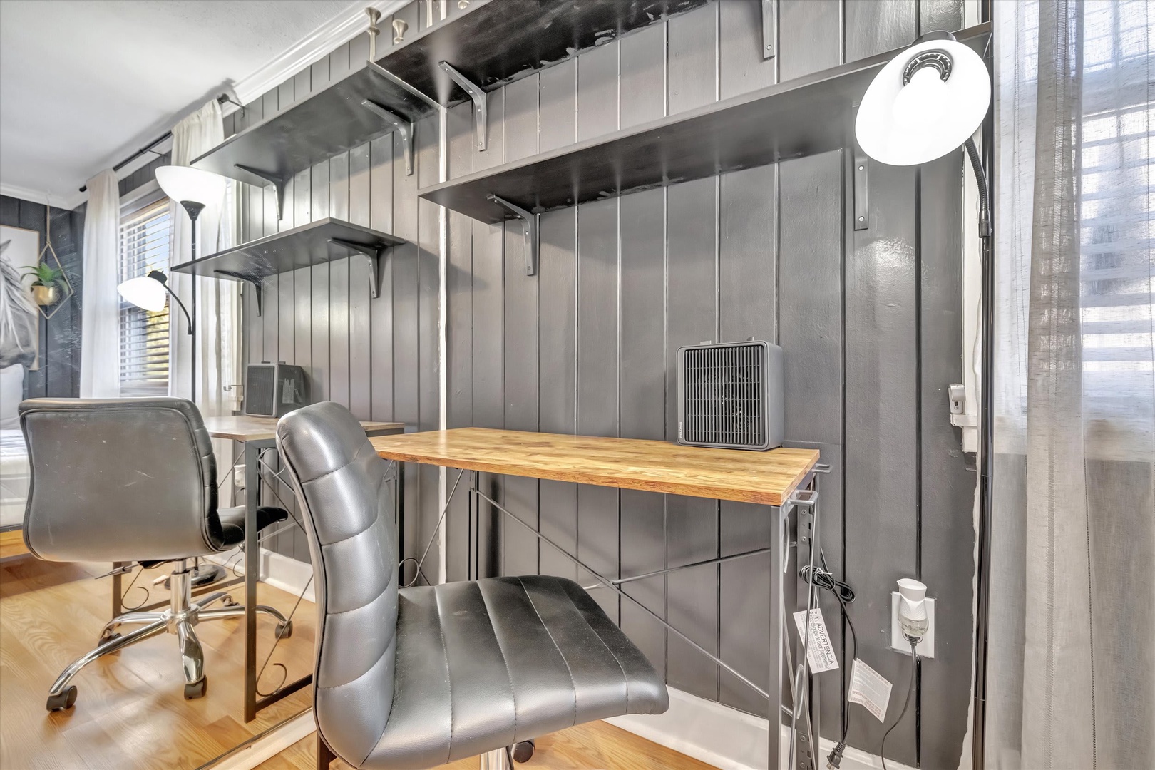 Your dedicated workspace features a modern industrial desk setup with comfortable seating and natural light, perfect for remote work or catching up on emails during your stay.