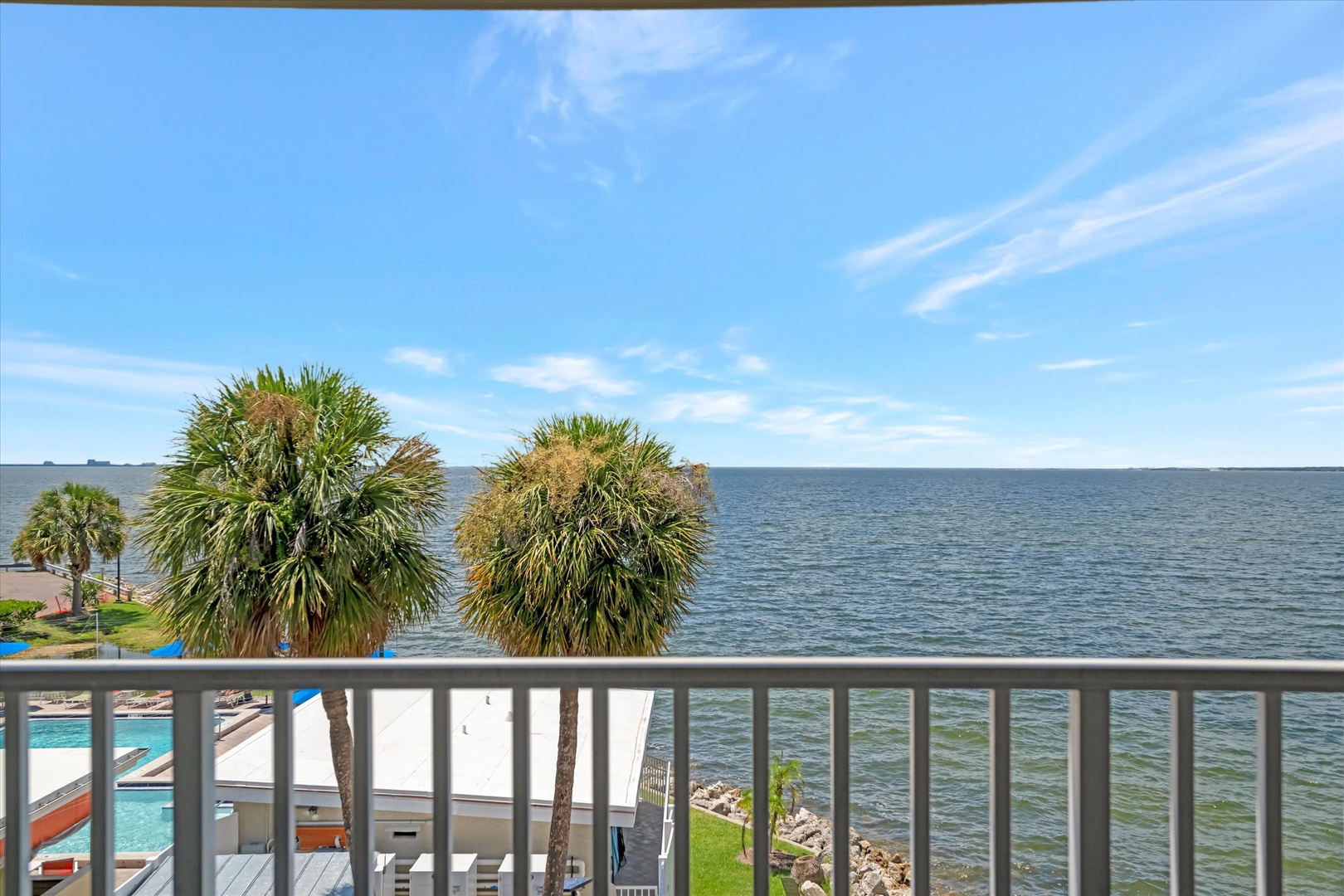 Sweeping water views stretch across the horizon from your private balcony, where palm trees frame a tranquil waterfront setting that's yours to enjoy throughout your stay.