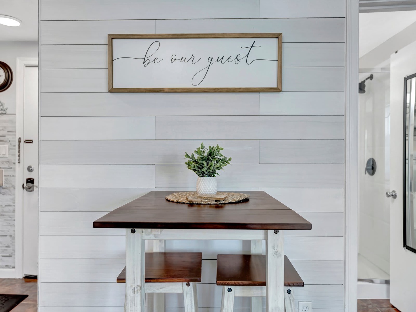 Your inviting dining nook awaits with its charming farmhouse style and warm welcome sign reminding you to relax and feel at home.