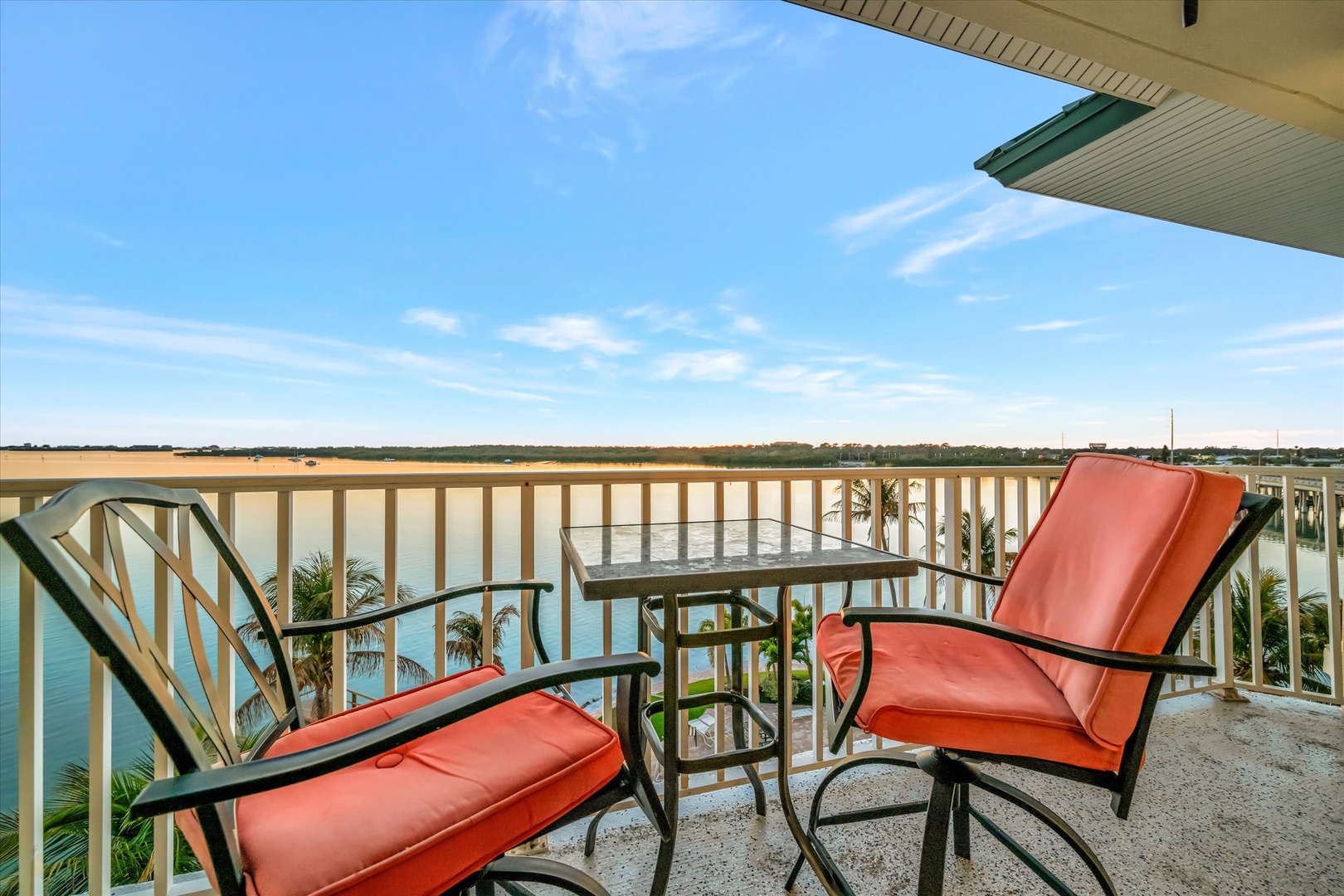 Relax on your private balcony with sweeping water views and tropical palm trees framing the horizon—a perfect spot for morning coffee or sunset moments.
