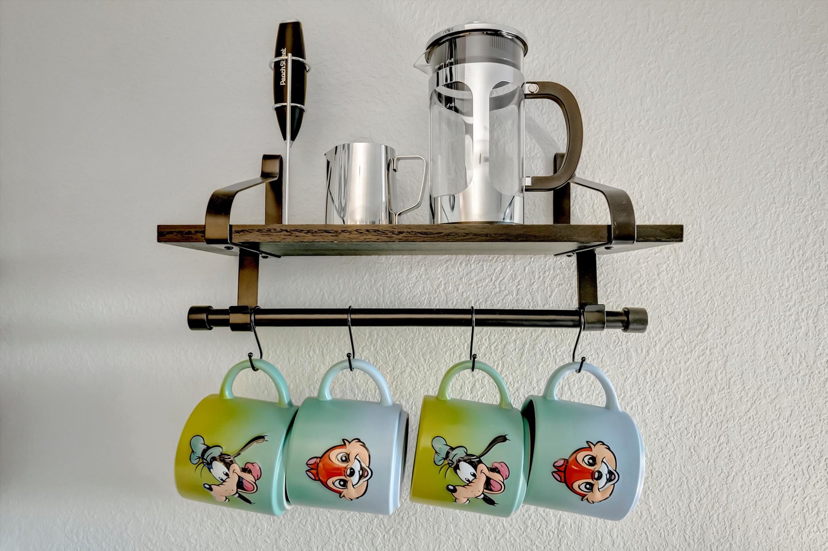 Your morning coffee routine gets a fun upgrade with this stylish station—complete with a sleek french press, stainless steel mugs, and cheerful character mugs hanging ready for use.