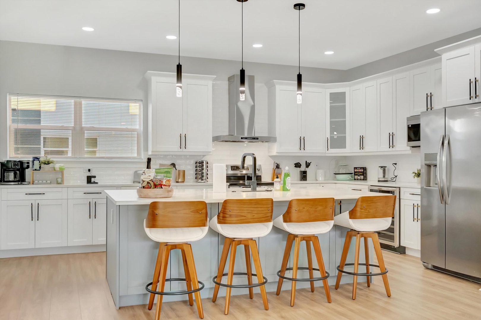 Gather around the spacious kitchen island where crisp white cabinetry and modern pendant lights create a bright, welcoming space for your morning coffee or meal prep during your stay.