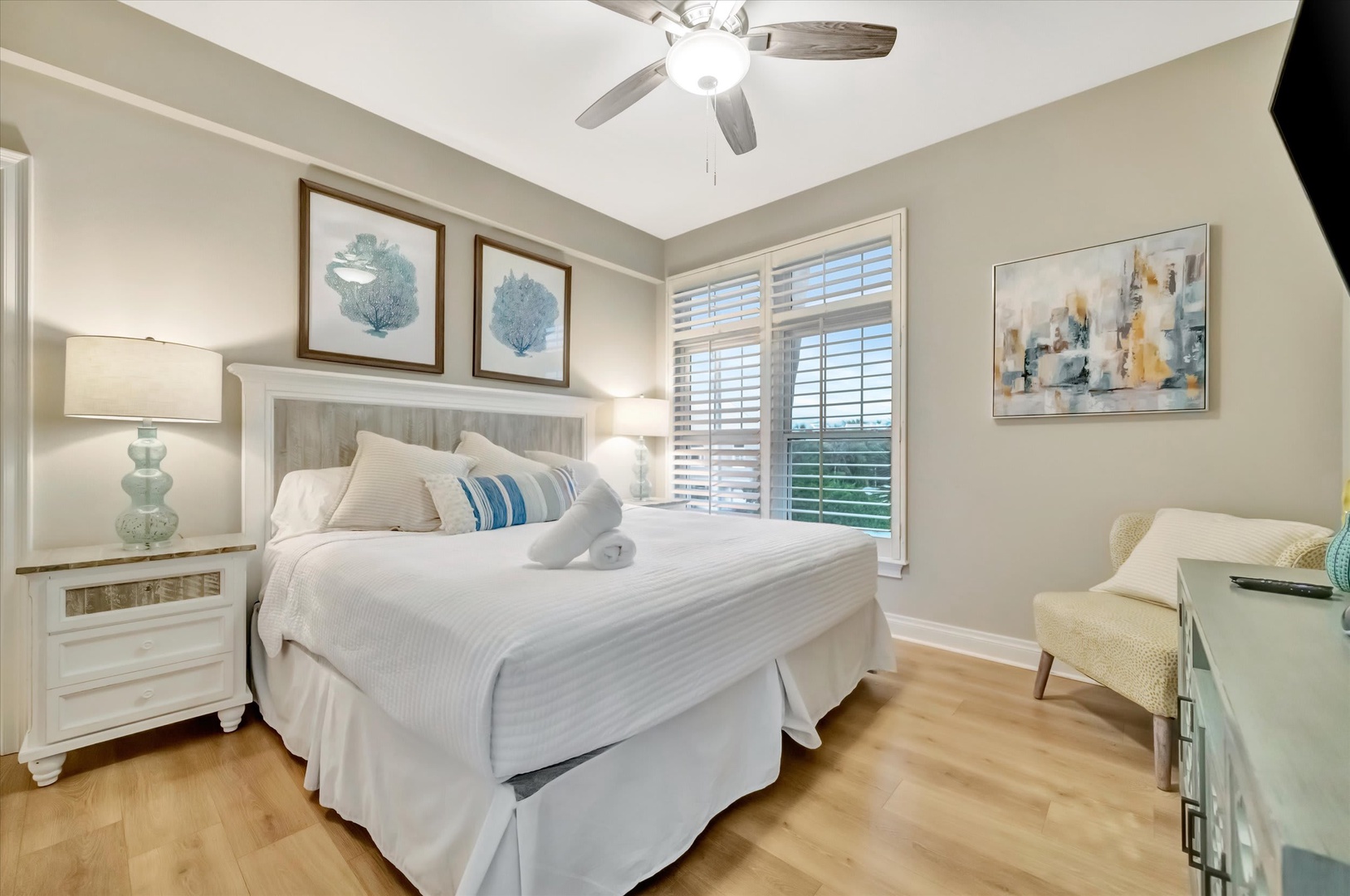 Sink into crisp white linens and gentle coastal decor after a day of adventure. Soft natural light filters through plantation shutters, while the ceiling fan keeps you comfortable.