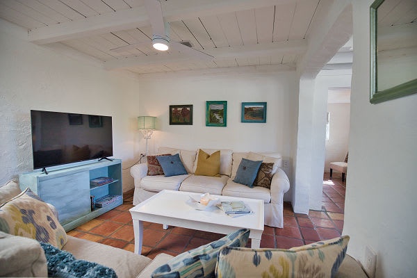 Settle into your cozy living space, where rustic terracotta floors meet whitewashed walls and a charming wood-planked ceiling, creating the perfect retreat for relaxed evenings together.