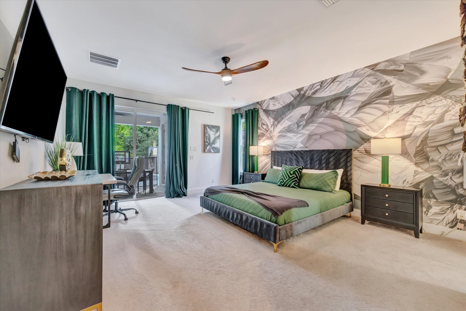 Your spacious bedroom invites rest with a dramatic accent wall, plush bedding in soothing greens, and a peaceful view of the outdoors through the sliding doors.
