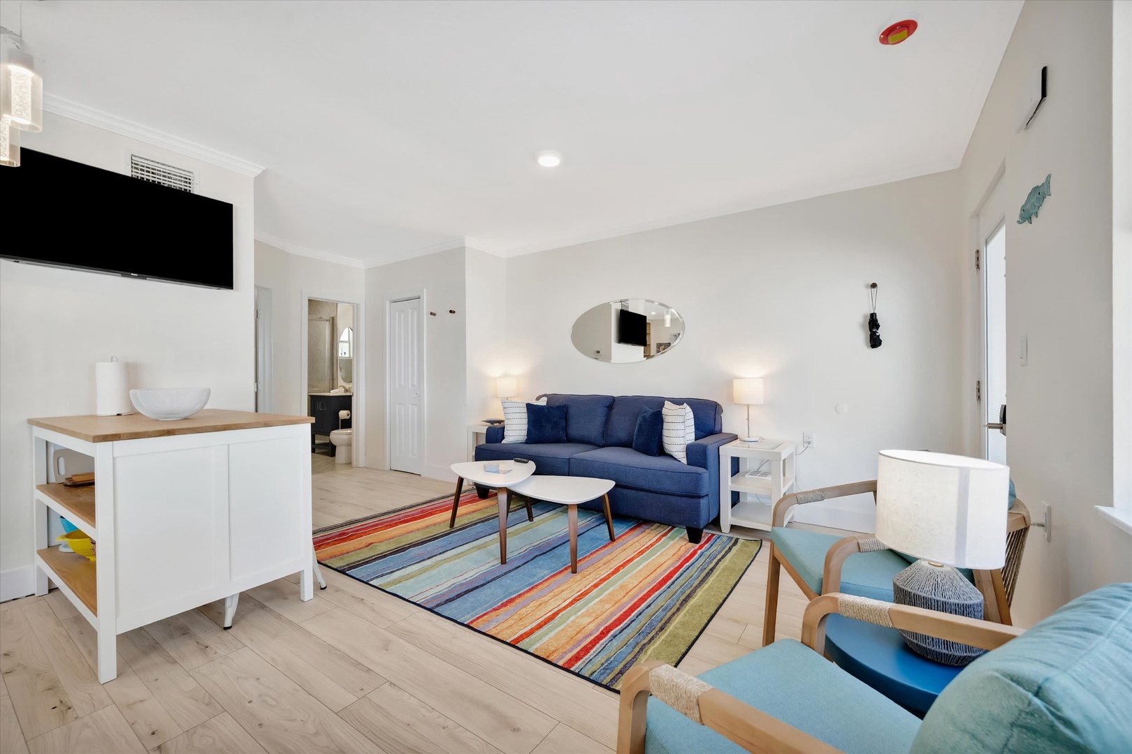 Step into your bright, coastal-inspired living space where pops of color meet comfortable seating. Sink into the blue sofa or turquoise accents and feel the coastal breeze in every detail—perfect for unwinding after a beach day.