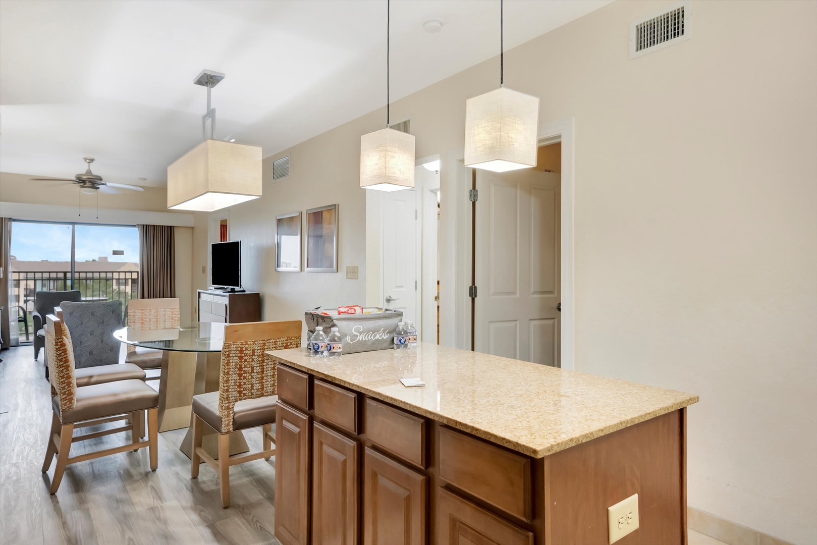Bright, open-concept living space with modern pendant lights, spacious kitchen island, and airy vaulted ceilings. Seamless flow to a private balcony—the perfect retreat.