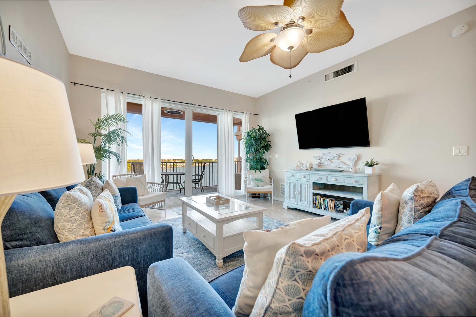 Sink into plush sofas beneath a tropical ceiling fan, where natural light floods in through balcony doors revealing your private ocean view. This bright, airy living room is perfect for unwinding after beach days.