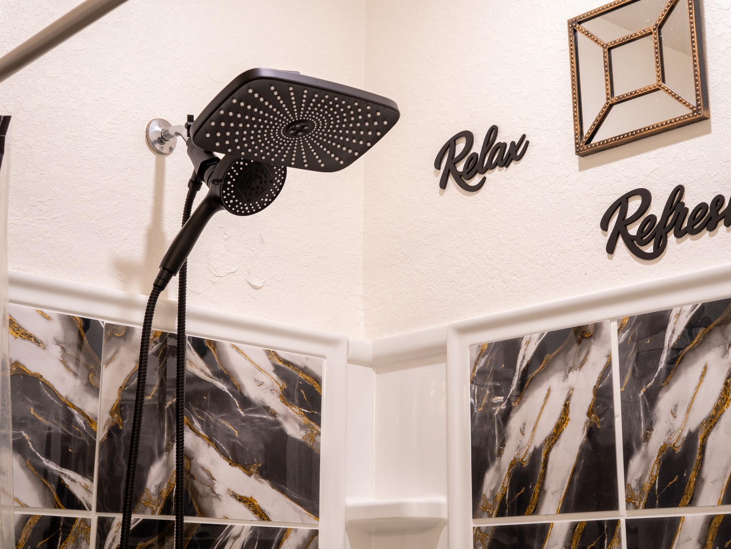 Step into your spa-like retreat and let the day's tension melt away beneath the rainfall showerhead. The elegant marble-toned tile and thoughtful touches invite you to truly unwind.