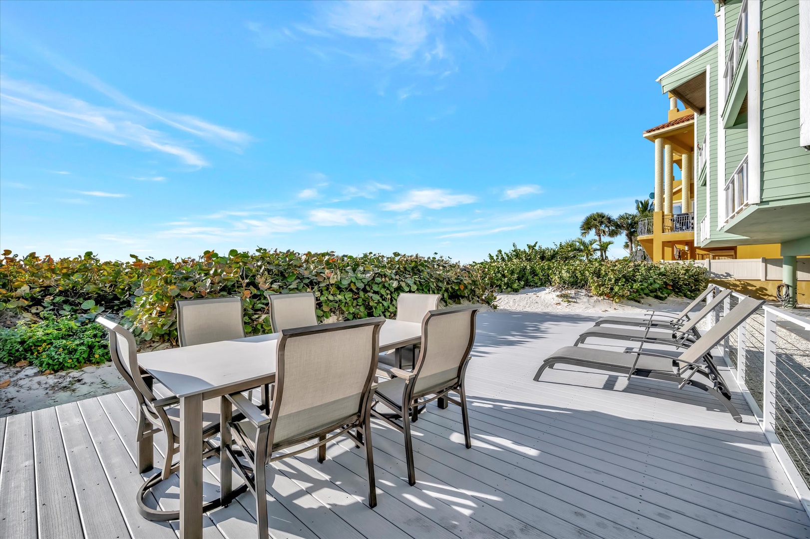 Step onto your private beachfront deck where turquoise skies meet soft sand, framed by lush coastal greenery. Dine al fresco or lounge in the sun—your perfect escape awaits.