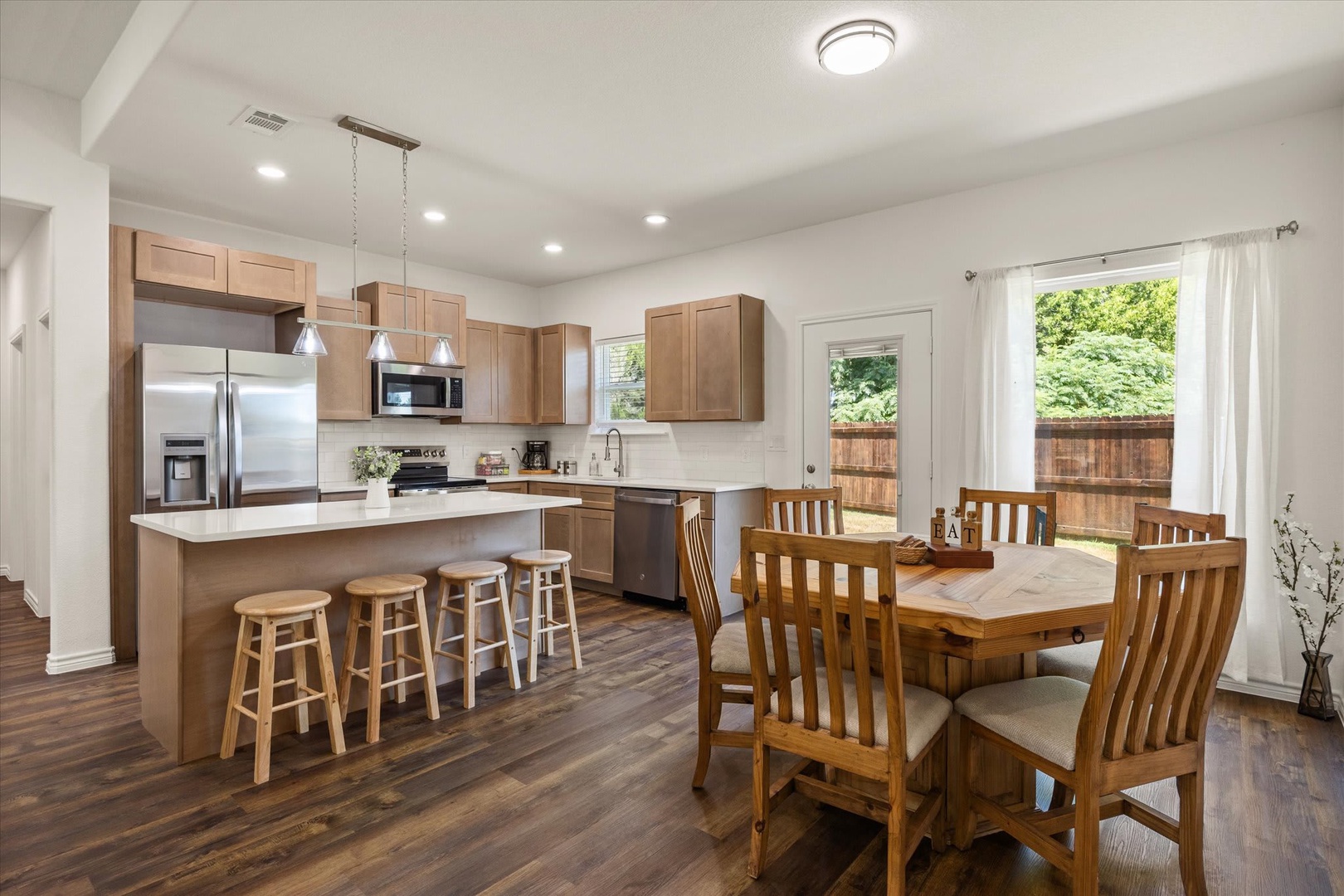 Picture your group gathering in this open, sun-lit kitchen and dining area, where everyone can help with meals and share stories around the island or dining table. Natural light pours in, creating a warm, inviting space for making memories together.