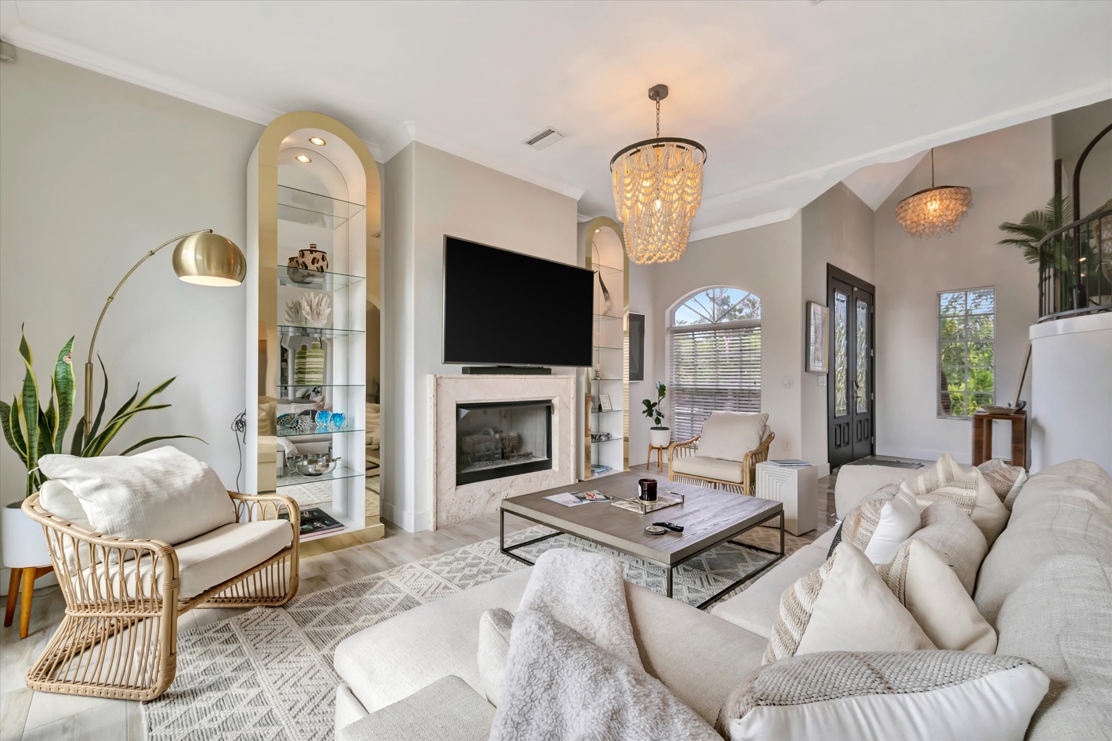Sink into plush seating under elegant chandeliers in your spacious living room, where a cozy fireplace and abundant natural light create the perfect retreat after a day of exploring.