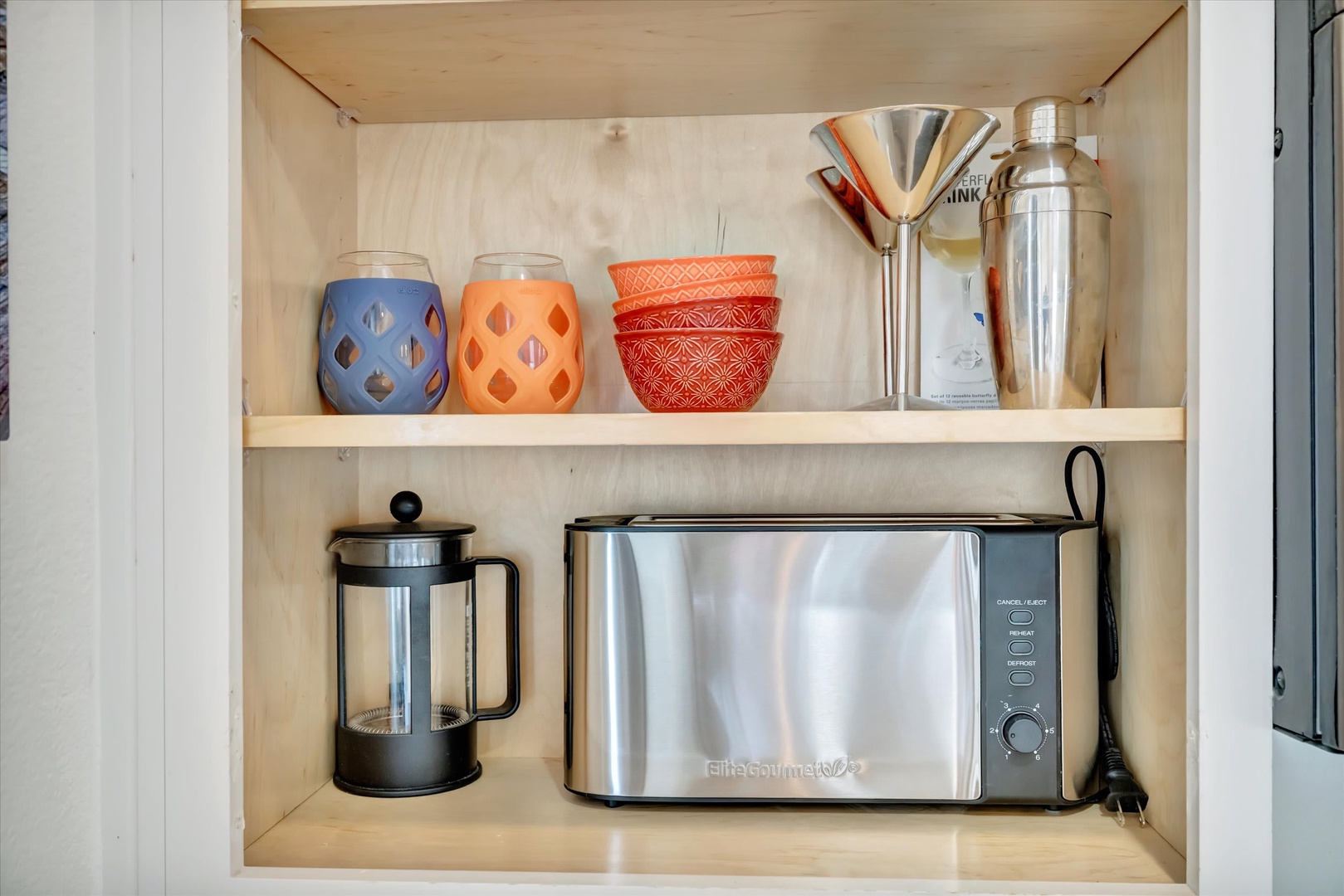 Your kitchenette shelves are thoughtfully stocked with everything you need for morning coffee or a light meal—colorful drinkware, a French press, and a sleek toaster ready for your use.