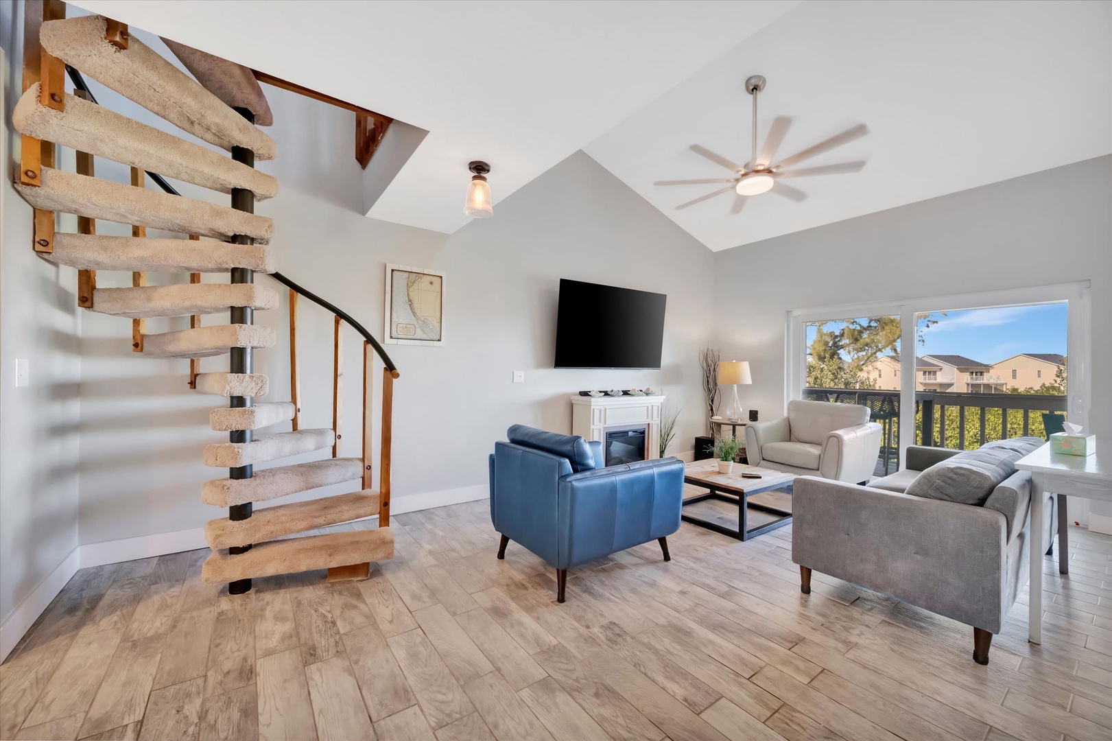 Settle into your bright, airy living room with soaring ceilings and sunshine streaming through large windows. Relax on plush seating, enjoy the TV for movie nights, and let the spiral staircase lead you to your upstairs retreat.