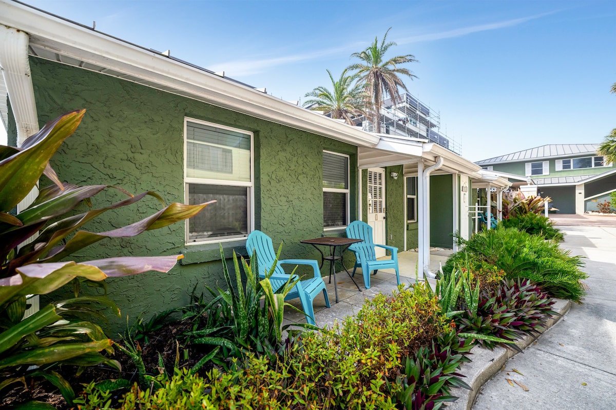 A colorful coastal retreat with tropical gardens and bright Adirondack chairs on your private patio, perfect for morning coffee or sunset cocktails.