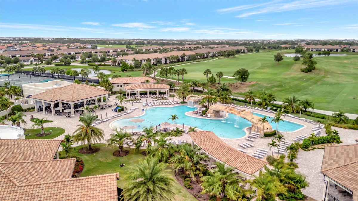 Aerial view of the resort complex featuring a resort-style pool, clubhouse, and adjacent golf course within a landscaped residential community.