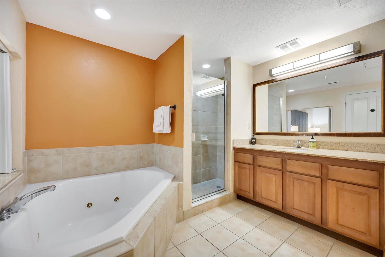 Your spacious bathroom invites pure relaxation with warm tones, a deep soaking tub, and a separate glass-enclosed shower—everything you need to refresh and unwind in style.