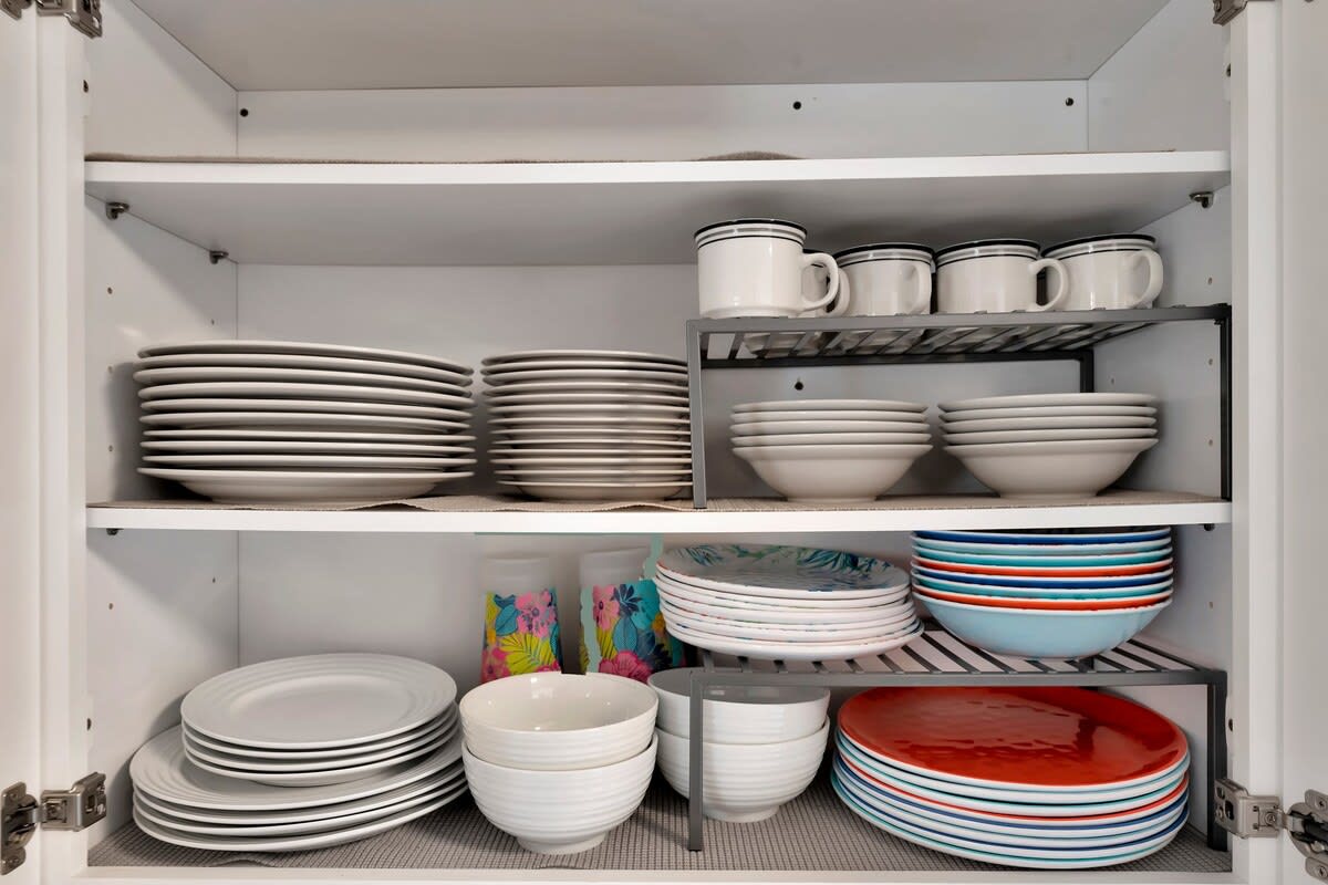Your kitchen is fully stocked with everything you need—plates, bowls, mugs, and colorful dinnerware neatly organized and ready for home-cooked meals or morning coffee.