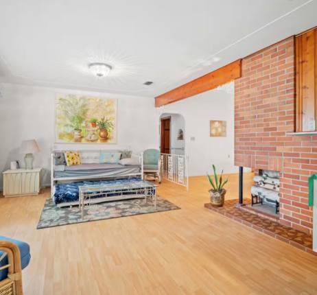 Unwind in your spacious living room with warm wood floors, exposed brick fireplace, and natural light streaming in—perfect for relaxing after exploring the area.